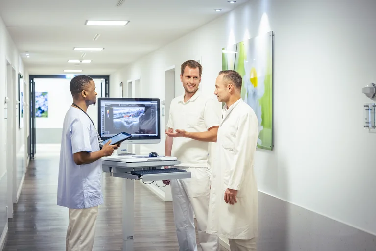 Assistenzarzt Rheumatologie bei der Visite mit dem Klinikdirektor und einer Pflegekraft