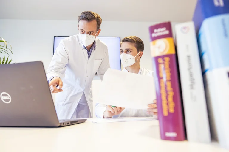 Zwei Ärzte tauschen sich am Schreibtisch aus