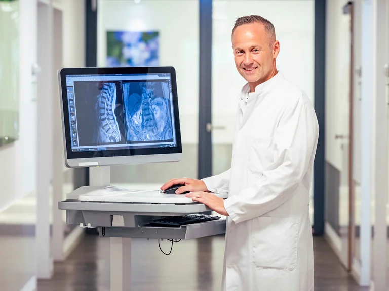 Prof. Dr. Xenofon Baraliakos, Ärztlicher Direktor des Rheumazentrum Ruhrgebiet, mit den Bildern einer Patientin, die an Spondyloarthritis erkrankt ist.