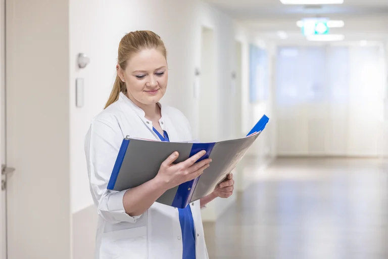 Eine Assistenzärztin mit einer Patientenakte