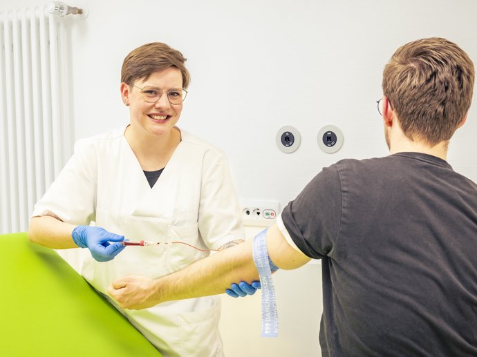 Eine Pflegefachfrau nimmt bei einem Patienten in der Armbeuge Blut ab