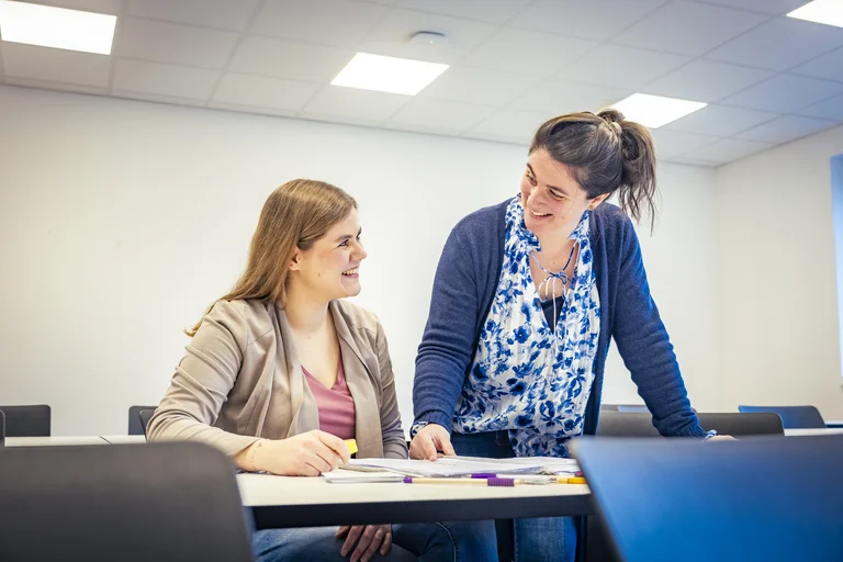 Lehrkraft erklärt der Auszubildenden etwas im Klassenraum