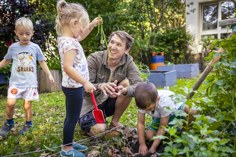 Ein Erzieher der Kindertagesstätte spielt mit Kindern im Garten