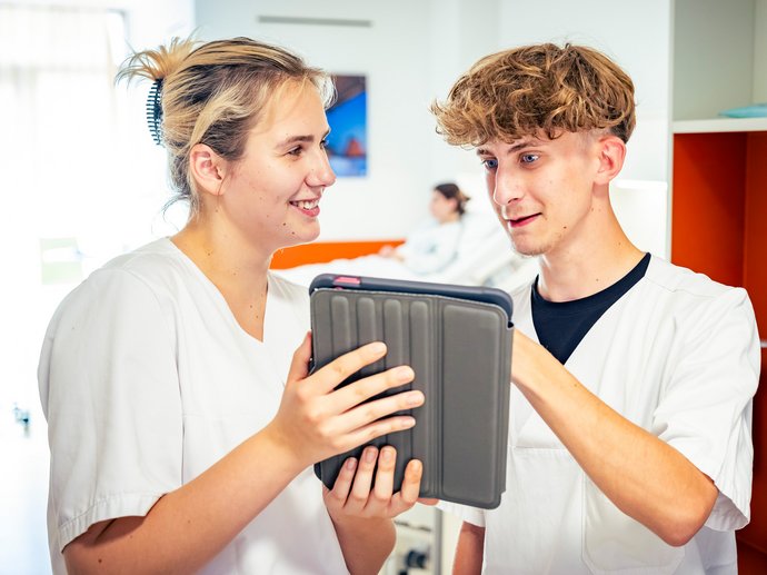 Zwei Pflegeauszubildende tauschen sich an einem Ipad aus