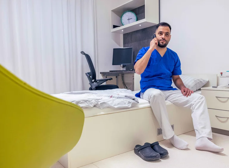 Ein Assistenzarzt wird im Bereitschaftszimmer nachts durch einen Anruf geweckt