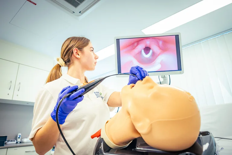 Logopädie-Auszubildende führt eine Untersuchung mit einer Modellpuppe durch