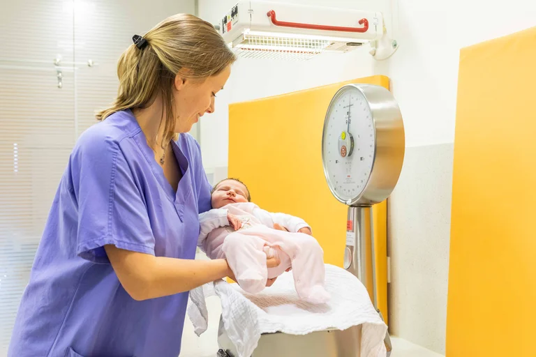Hebamme wiegt Säugling