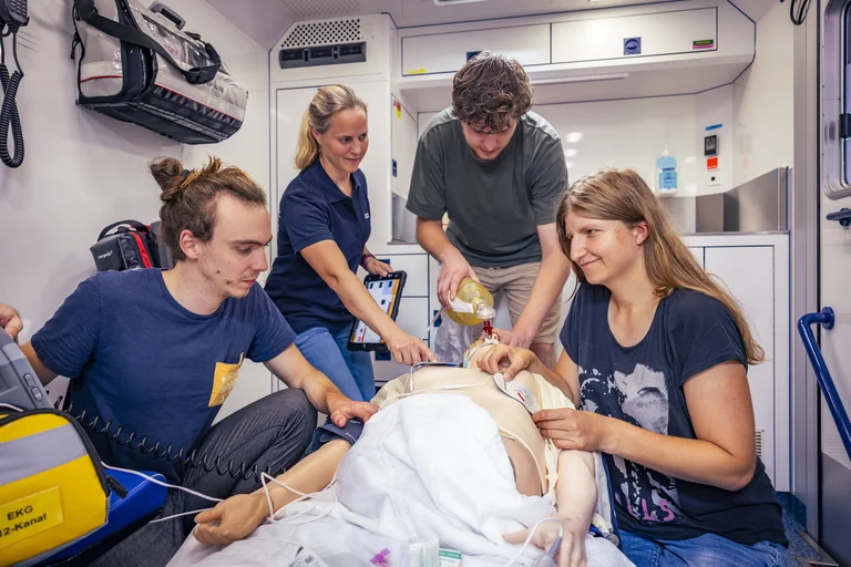Studierende werden von einer Ärztin bei einer Übung angeleitet