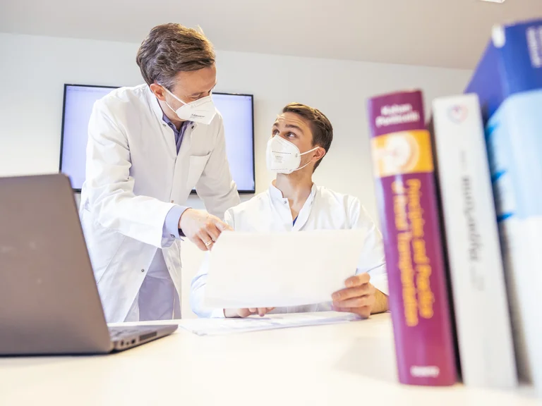 Assistenzarzt Innere Medizin am Schreibtisch mit dem Klinikdirektor