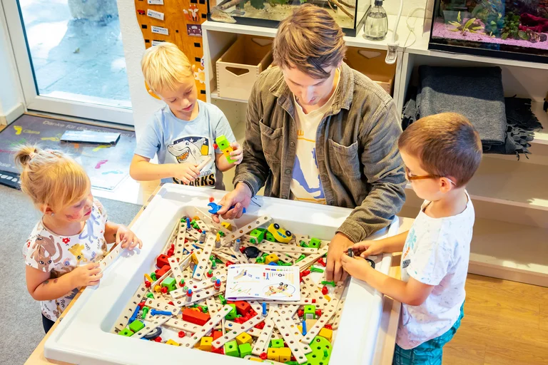 Kinder spielen mit einem Erzieher